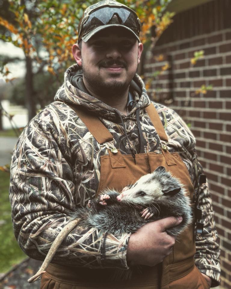 A worker from Lone Star Animal Removal carrying a possum